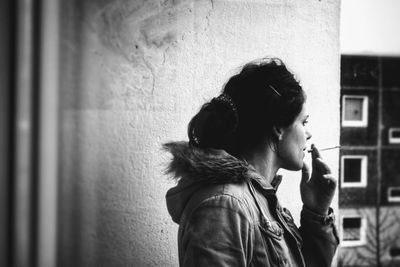 Portrait of young woman standing against wall