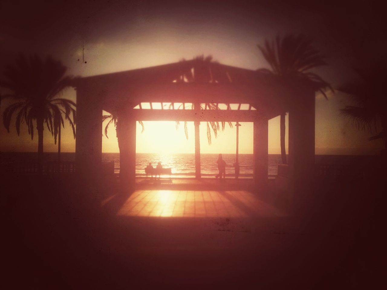 palm tree, sunset, silhouette, sea, beach, sun, horizon over water, built structure, sunlight, tree, sky, water, tranquility, architecture, tranquil scene, nature, beauty in nature, sunbeam, scenics, shore