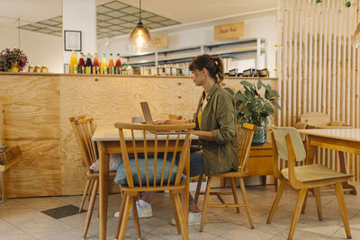 Female owner working on laptop while sitting in cafe