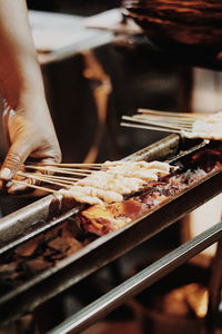 Close-up of person preparing food on barbecue grill