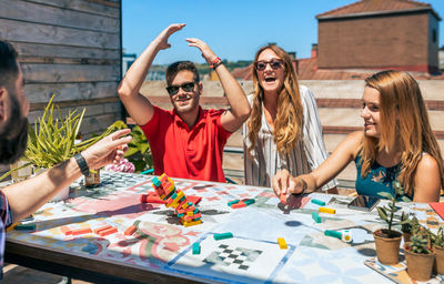 Group of friends laughing while young man lose in jenga game in a rooftop party