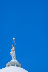 Low angle view of statue against blue sky