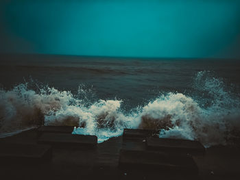 Sea waves splashing on shore against clear sky