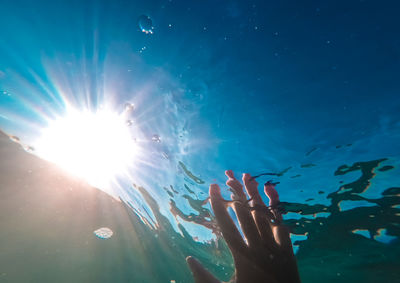 The hand reaches out to the sun from under the water