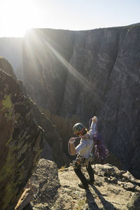 High angle view of man with rope standing on mountain against sky during sunny day