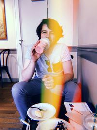 Young man drinking glass on table at home