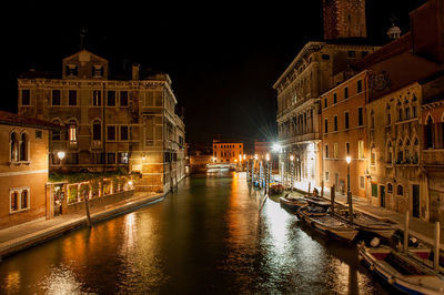 Canal amidst buildings in city at night