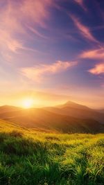 Scenic view of rolling landscape against sky during sunrise 