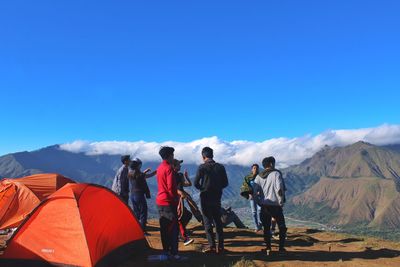 Rear view of people on mountain against blue sky