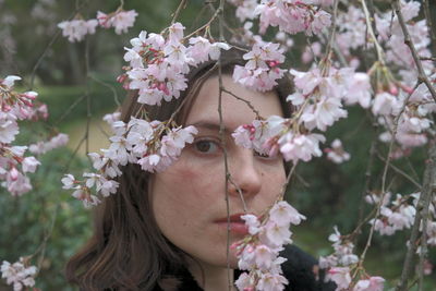 Close-up portrait of beautiful woman against white flowering plants