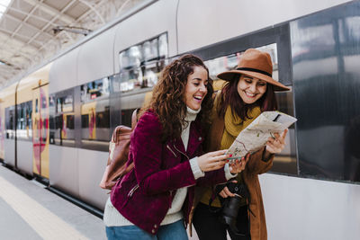 Friends reading map at railroad station platform