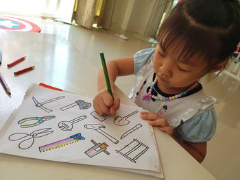 High angle view of cute girl drawing in book on table