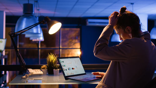 Rear view of man using laptop at table