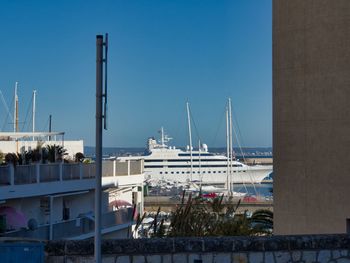 Sailboats in city against clear blue sky