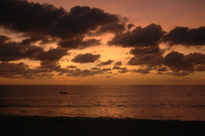 Scenic view of sea against dramatic sky during sunset