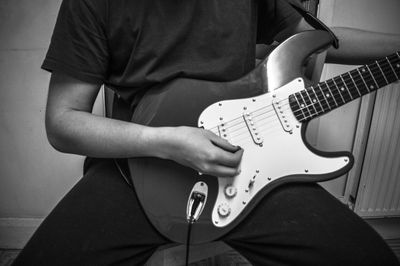 Midsection of man playing electric guitar