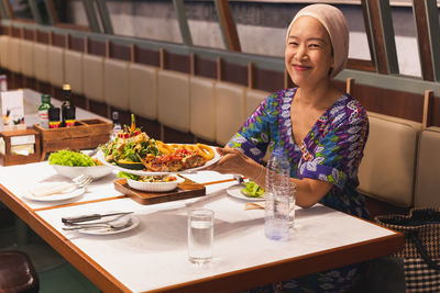 Happy woman holding a plate of grilled chicken at lunch time