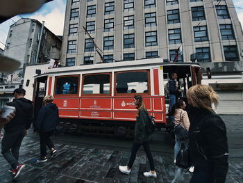 Rear view of people walking on train in city