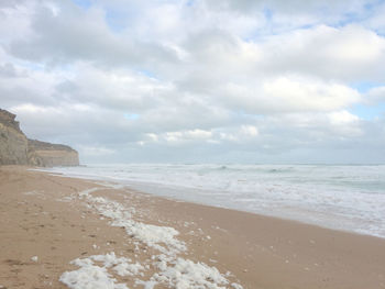 Scenic view of beach against cloudy sky