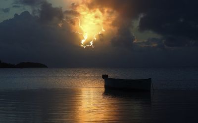 Silhouette boat in sea against sky during sunset