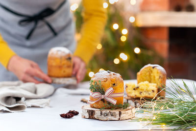 Traditional italian christmas cake panettone on a rustic table. female hands are holding cake