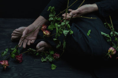 Dead roses and woman in black linen dress as symbol for divorce or a weeping widow
