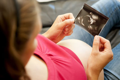 High angle view of pregnant woman holding x-ray at home