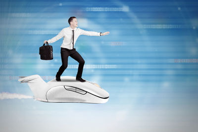 Digital composite image of businessman standing on computer mouse