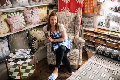 Portrait of confident female owner sitting on chair at fabric shop