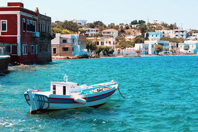 Boat in sea by buildings against clear sky