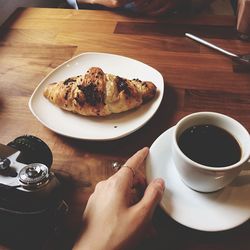 Cropped hand of woman with black coffee at table