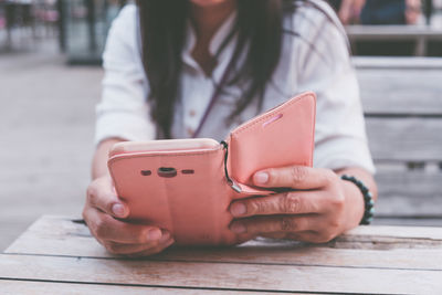 Midsection of young woman using phone on table