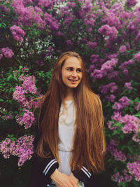 Portrait of smiling woman standing by flowering plants