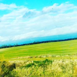Scenic view of grassy field against cloudy sky