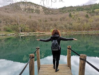 Rear view of woman walking on pier over lake