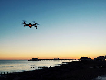 Silhouette of helicopter in sea against clear sky