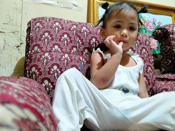 Portrait of cute girl sitting on bed at home