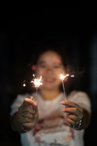 Close-up of woman holding sparklers at night