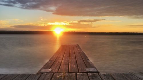 Pier in sea at sunset