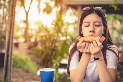 Close-up of young woman eating food while sitting outdoors