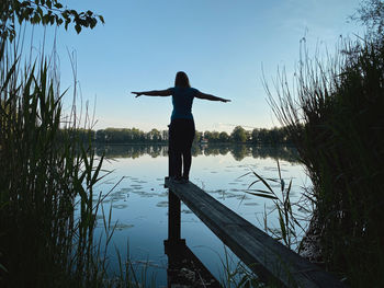 Rear view of man standing by lake against sky