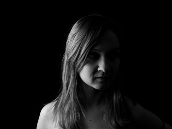 Close-up portrait of a young woman over black background