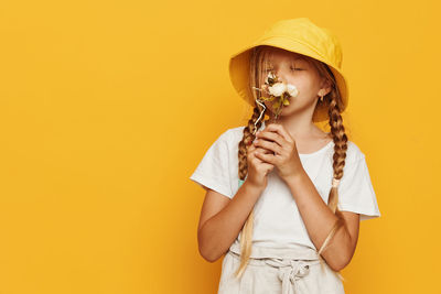 Midsection of woman holding bottle against yellow background