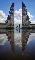 Reflection of woman in lake against sky