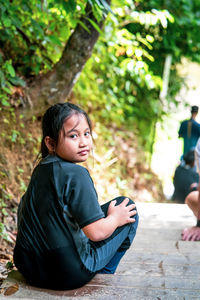 Portrait of a young child resting and sitting on the stairs during jungle trekking in the forest.