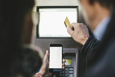 Senior couple making payment through credit card and mobile phone at bike rental station