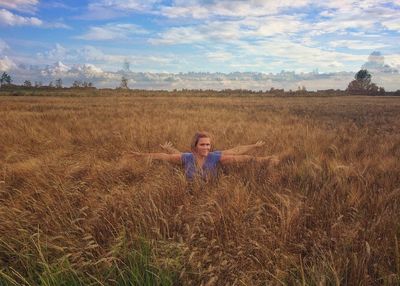 Portrait of young woman standing on field against sky