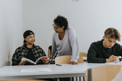 Teacher looking at smiling male student sitting in classroom