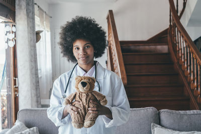 Doctor holding teddy bear at home