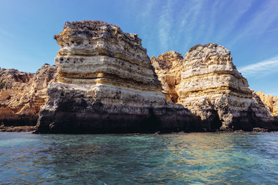 Rock formation in sea against blue sky